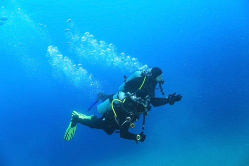 Scuba divers in open water blue sea.