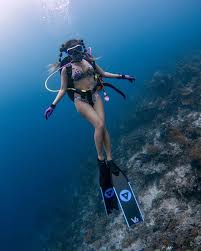Girl with pig tails poses for the camera while scuba diving with nitrox.